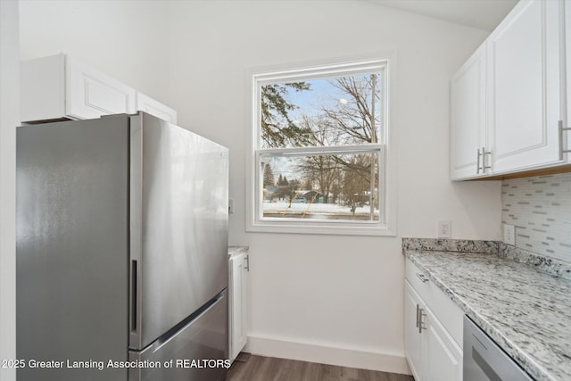 kitchen with stainless steel refrigerator, white cabinetry, dark hardwood / wood-style floors, and light stone countertops