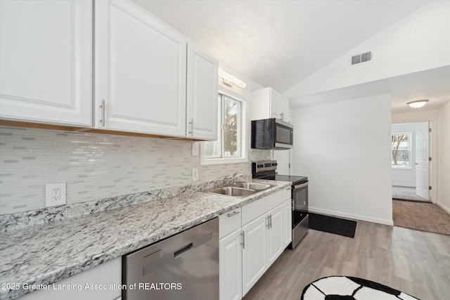 kitchen with stainless steel appliances, vaulted ceiling, sink, and white cabinets