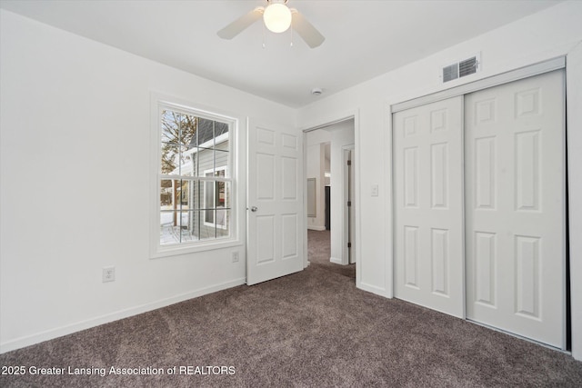 unfurnished bedroom featuring ceiling fan, dark carpet, and a closet