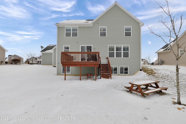 snow covered back of property with a wooden deck