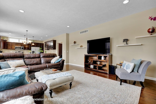 living room featuring dark wood-type flooring, a chandelier, and a textured ceiling