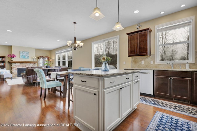 kitchen with sink, hanging light fixtures, dark brown cabinetry, white cabinets, and light wood-type flooring