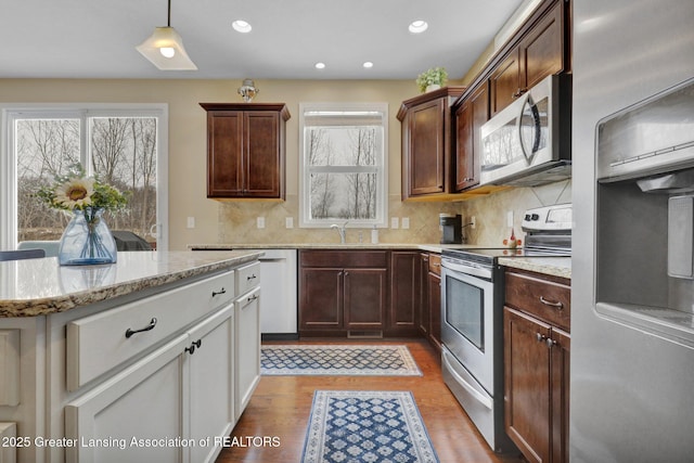 kitchen with light hardwood / wood-style flooring, hanging light fixtures, stainless steel appliances, tasteful backsplash, and a kitchen island