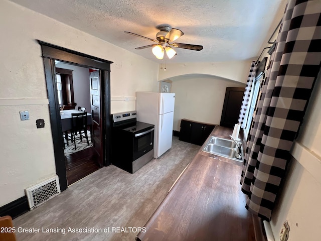 kitchen with sink, stainless steel electric range oven, a textured ceiling, white refrigerator, and hardwood / wood-style floors