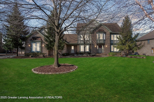 english style home with brick siding and a front yard