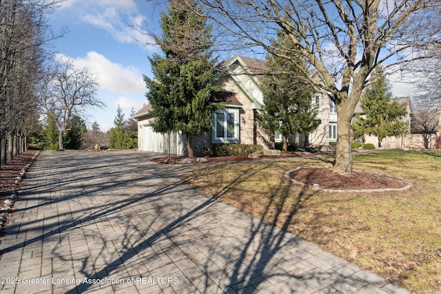 obstructed view of property featuring a front lawn, an attached garage, and driveway