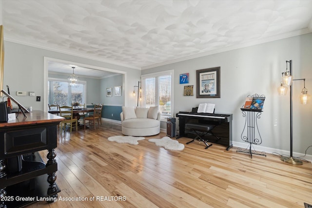 living area with a chandelier, ornamental molding, baseboards, and hardwood / wood-style flooring