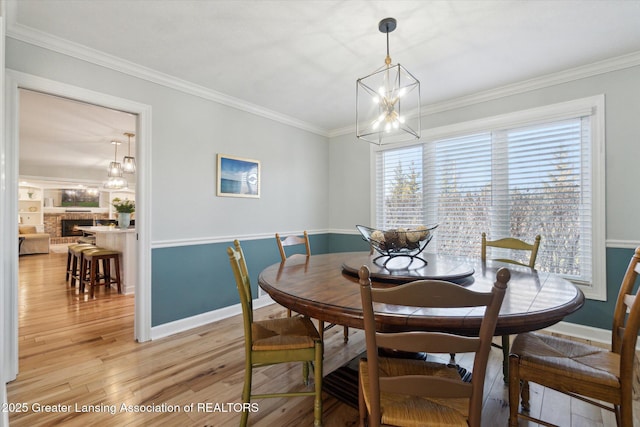 dining space with crown molding, light wood-style flooring, a notable chandelier, and baseboards