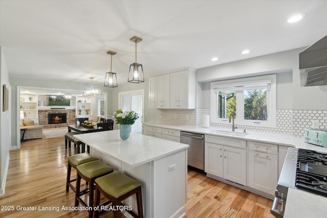 kitchen featuring a sink, a kitchen island, light wood-type flooring, and stainless steel dishwasher