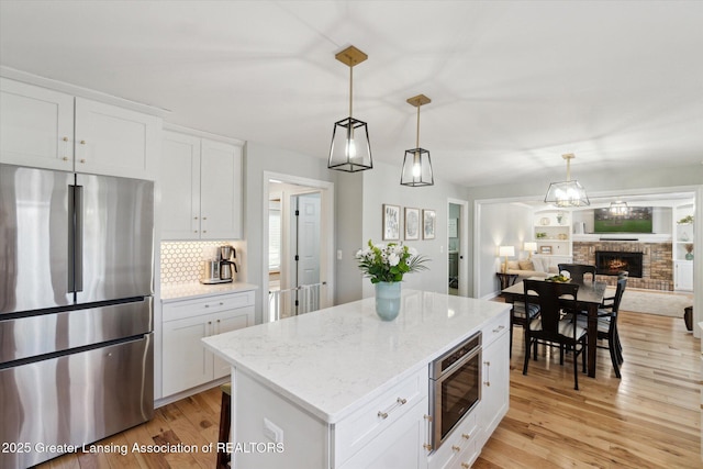 kitchen featuring light wood finished floors, freestanding refrigerator, white cabinetry, open floor plan, and a center island