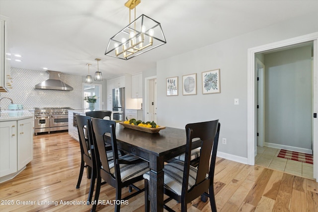 dining space with an inviting chandelier, baseboards, and light wood-type flooring