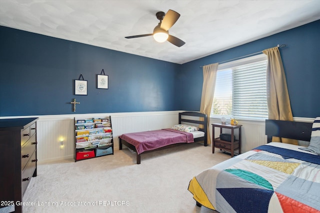 bedroom with a wainscoted wall, ceiling fan, and carpet floors