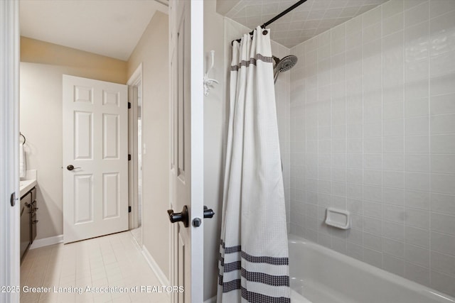 full bath featuring tile patterned flooring, shower / tub combo, vanity, and baseboards