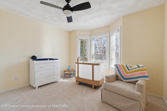 living area with a ceiling fan, light colored carpet, and baseboards