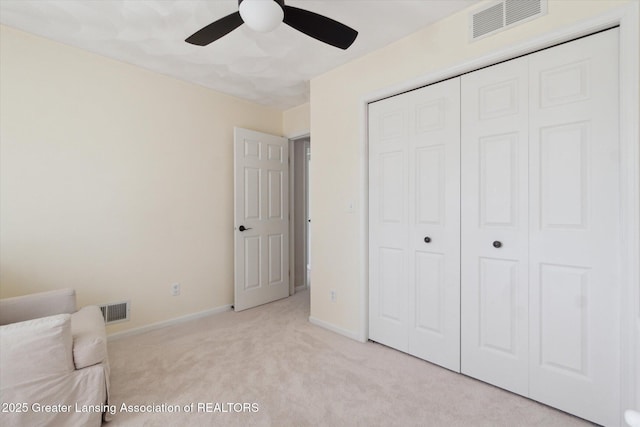 interior space featuring baseboards, a ceiling fan, visible vents, and light carpet