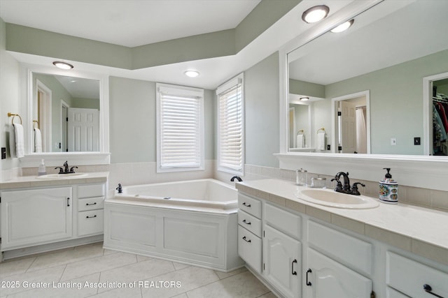 full bathroom with a sink, a garden tub, two vanities, and tile patterned floors