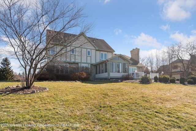 back of property featuring a chimney, a yard, and a sunroom