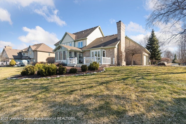 rear view of property with an attached garage, a lawn, a sunroom, and a chimney