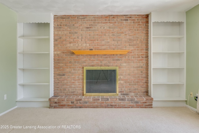 unfurnished living room with carpet flooring, a fireplace, and built in shelves