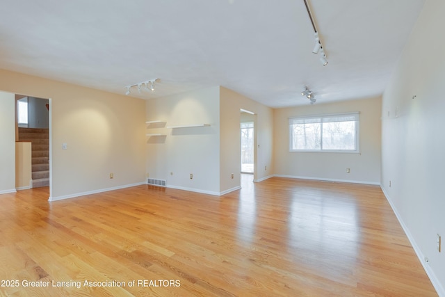 spare room with rail lighting and light hardwood / wood-style floors