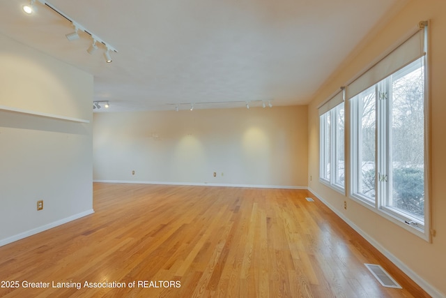 spare room featuring track lighting and light hardwood / wood-style floors