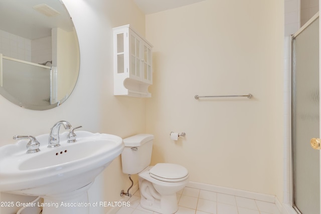 bathroom with a shower with door, sink, tile patterned floors, and toilet