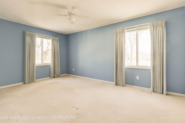 carpeted empty room with a wealth of natural light and ceiling fan