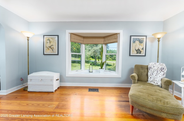 sitting room with baseboards, visible vents, and wood finished floors