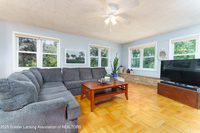 living area featuring ceiling fan and a textured ceiling