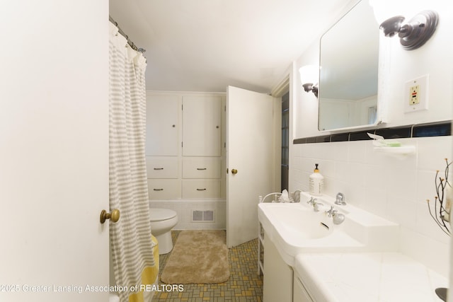 full bathroom featuring toilet, visible vents, vanity, tile walls, and tile patterned floors