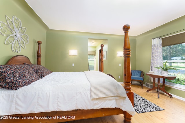 bedroom with baseboards, visible vents, and wood finished floors