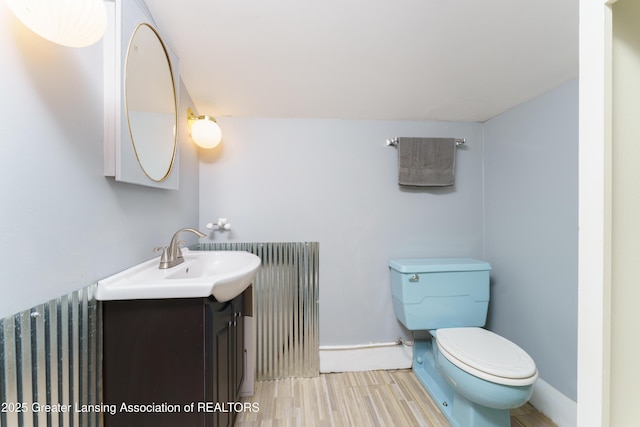 bathroom featuring toilet, baseboards, wood finished floors, and vanity