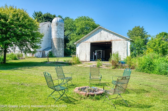 view of yard featuring a garage, an outdoor fire pit, an outdoor structure, and an outbuilding