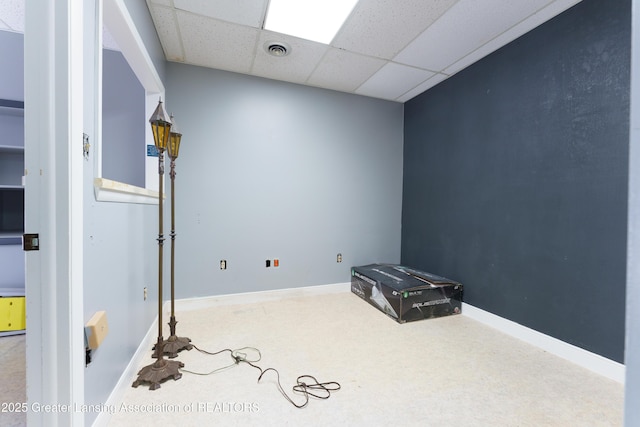 interior space with a paneled ceiling, baseboards, and visible vents