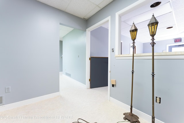 corridor featuring visible vents, carpet floors, a paneled ceiling, and baseboards