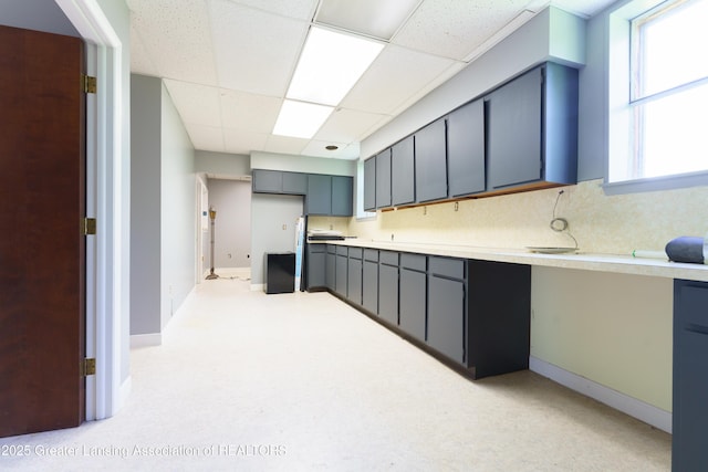 kitchen featuring tasteful backsplash, baseboards, light countertops, gray cabinetry, and a paneled ceiling