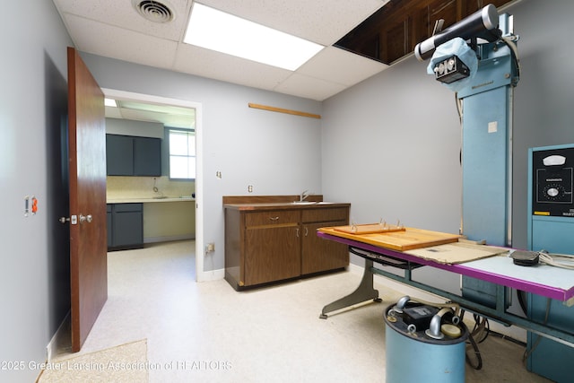 office area with a paneled ceiling, light floors, visible vents, and a sink