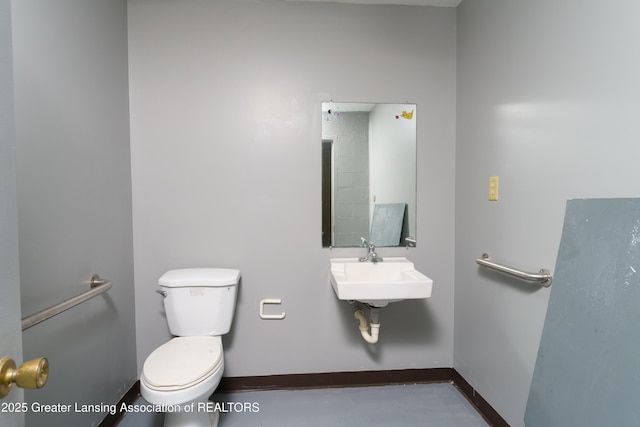 half bathroom featuring toilet, baseboards, and a sink