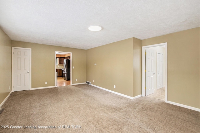 spare room with light carpet and a textured ceiling