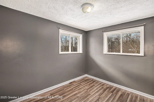 unfurnished room with a healthy amount of sunlight, wood-type flooring, and a textured ceiling