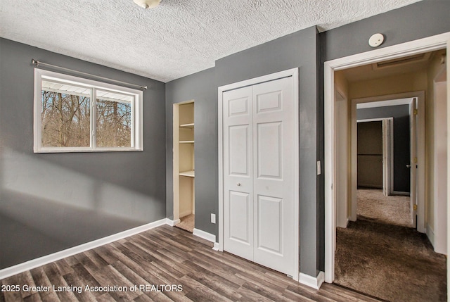 unfurnished bedroom featuring dark hardwood / wood-style flooring, a closet, and a textured ceiling