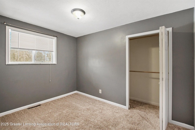 unfurnished bedroom with light colored carpet and a closet