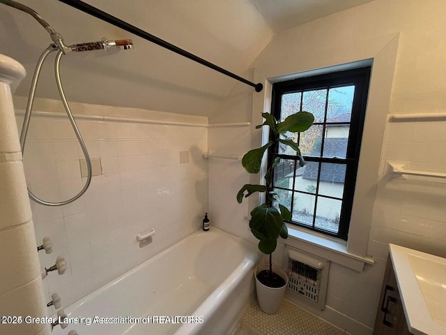 bathroom with tile walls, a wealth of natural light, shower / washtub combination, and heating unit