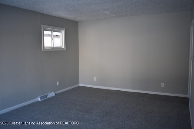 unfurnished room featuring a textured ceiling and dark colored carpet