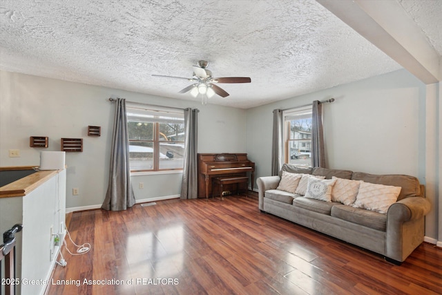 living room featuring ceiling fan, a textured ceiling, dark hardwood / wood-style floors, and a healthy amount of sunlight