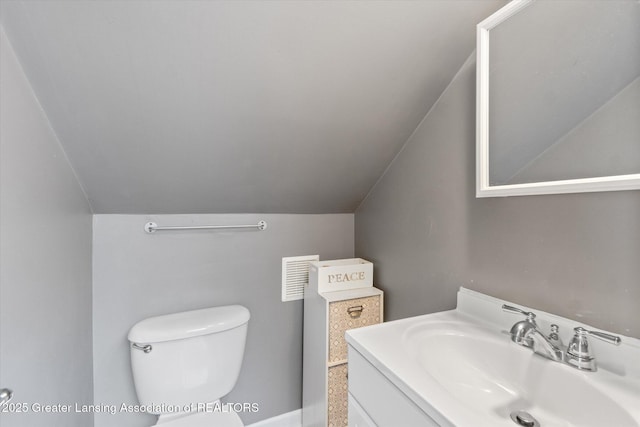 bathroom with vanity, vaulted ceiling, and toilet