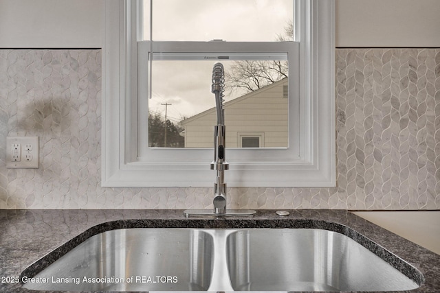 room details with dark stone countertops, sink, and white cabinets