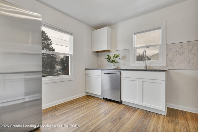 kitchen featuring appliances with stainless steel finishes, white cabinetry, sink, backsplash, and light hardwood / wood-style floors