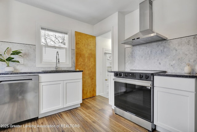 kitchen featuring white cabinetry, appliances with stainless steel finishes, sink, and wall chimney range hood