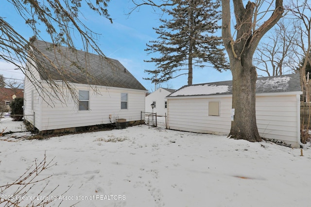 snow covered back of property featuring central AC unit